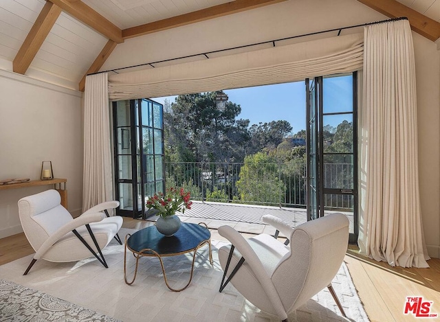 sitting room with plenty of natural light, light hardwood / wood-style flooring, and lofted ceiling with beams