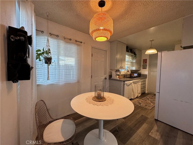 dining room with sink, dark wood-type flooring, and a textured ceiling