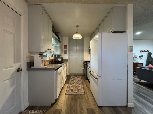 kitchen with white cabinetry, sink, white appliances, and hardwood / wood-style flooring