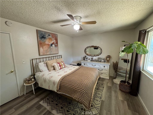 bedroom with dark wood-type flooring, a textured ceiling, and ceiling fan