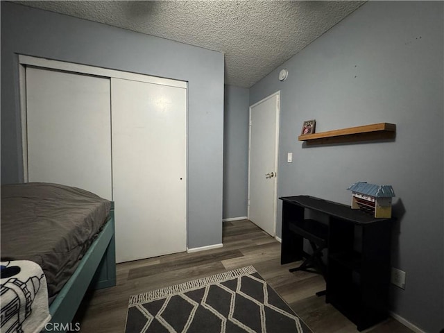 bedroom featuring a textured ceiling, dark hardwood / wood-style floors, and a closet