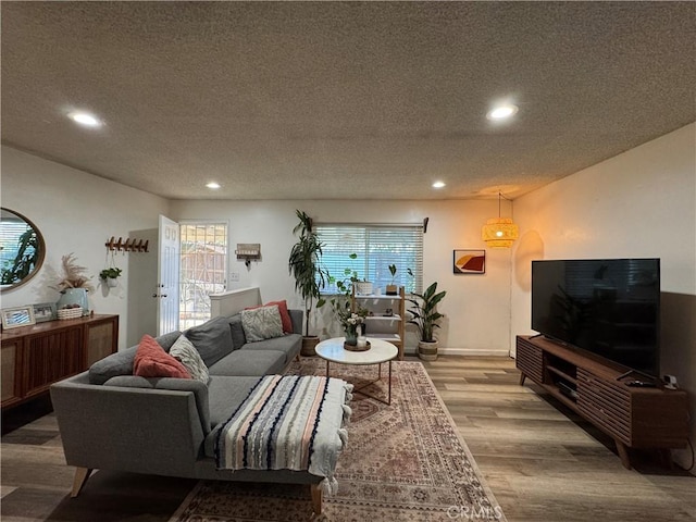 living room featuring a textured ceiling, hardwood / wood-style floors, and a healthy amount of sunlight