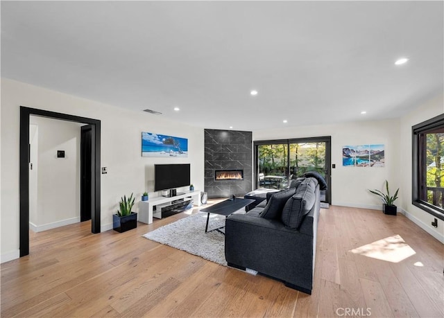 living room with a high end fireplace and light wood-type flooring