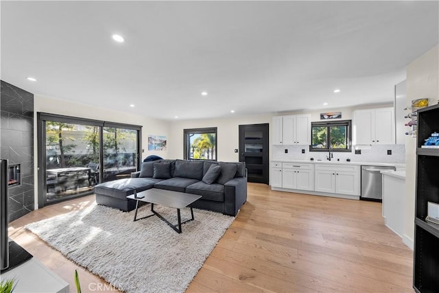 living room featuring sink, light hardwood / wood-style floors, and a wealth of natural light