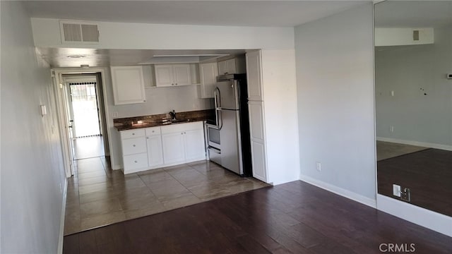 kitchen with stainless steel fridge, dark hardwood / wood-style flooring, sink, and white cabinets