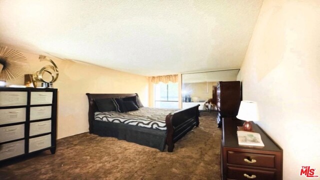 bedroom featuring dark colored carpet and a textured ceiling