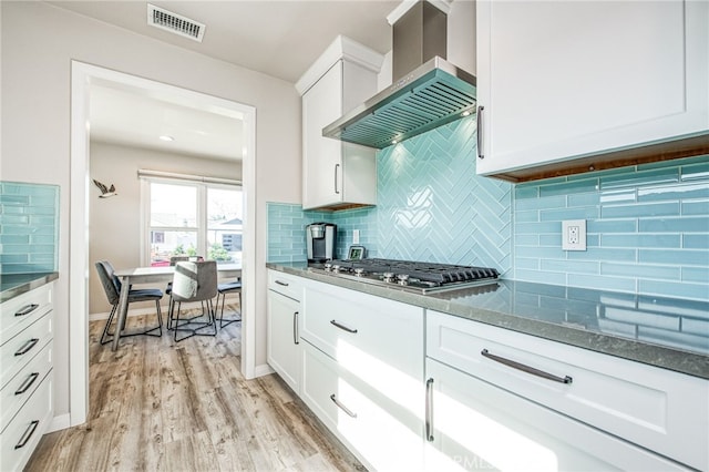 kitchen featuring decorative backsplash, white cabinets, and ventilation hood