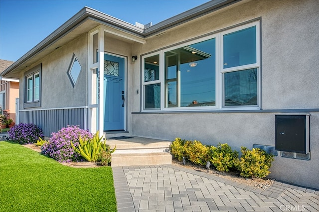 view of exterior entry featuring a lawn