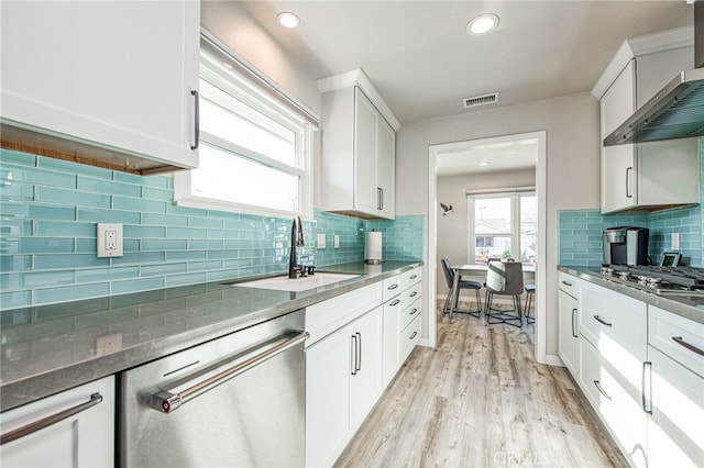 kitchen with white cabinetry, sink, wall chimney range hood, light wood-type flooring, and stainless steel appliances