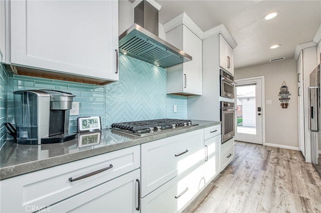 kitchen featuring stainless steel gas stovetop, white cabinetry, range hood, dark stone countertops, and backsplash