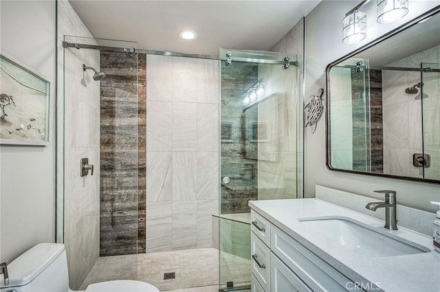 bathroom featuring a shower with door, toilet, and vanity