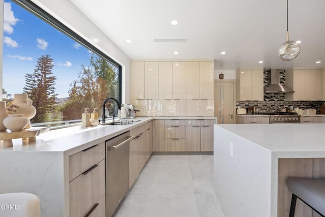 kitchen with light brown cabinets, pendant lighting, sink, wall chimney range hood, and stainless steel appliances