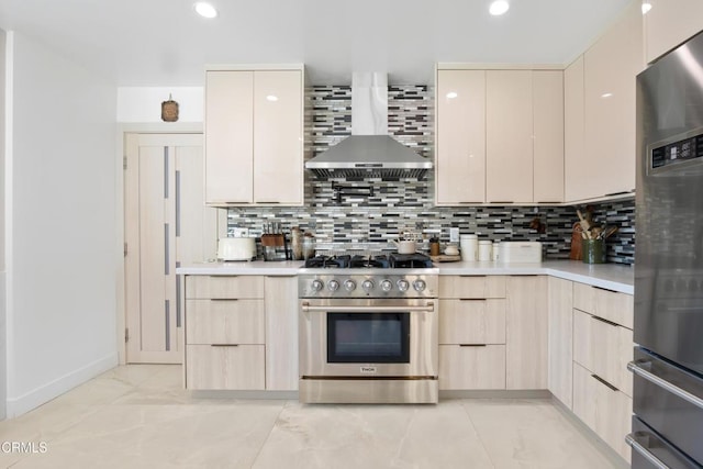 kitchen featuring wall chimney exhaust hood, light brown cabinets, backsplash, and stainless steel appliances