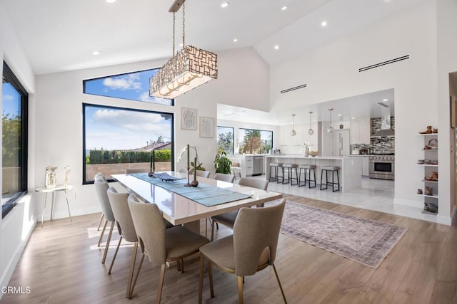 dining area featuring light hardwood / wood-style flooring and high vaulted ceiling