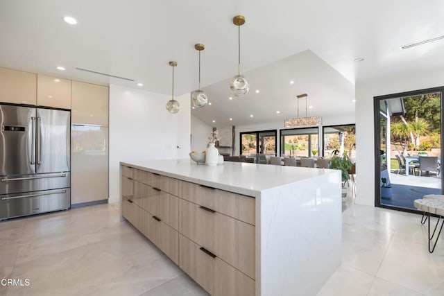 kitchen featuring hanging light fixtures, stainless steel refrigerator, light brown cabinets, and a spacious island