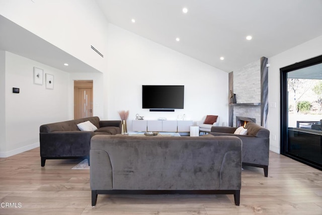 living room with high vaulted ceiling, light wood-type flooring, and a fireplace