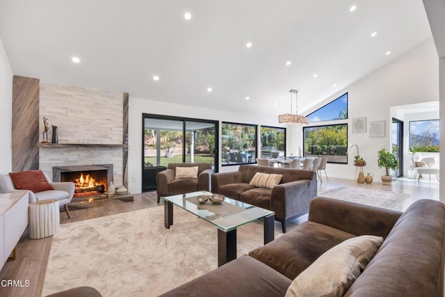 living room with high vaulted ceiling, light hardwood / wood-style flooring, a wealth of natural light, and a fireplace