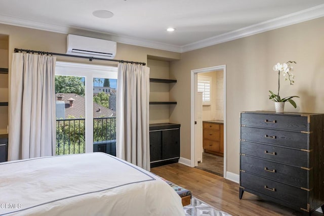 bedroom featuring hardwood / wood-style floors, ensuite bath, access to exterior, crown molding, and a wall mounted air conditioner