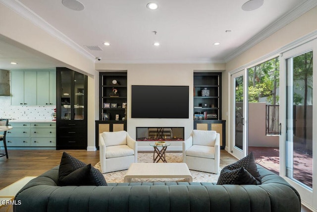 living room with built in shelves, light hardwood / wood-style floors, and crown molding