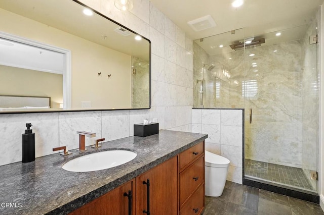 bathroom featuring vanity, toilet, tile walls, and a shower with shower door