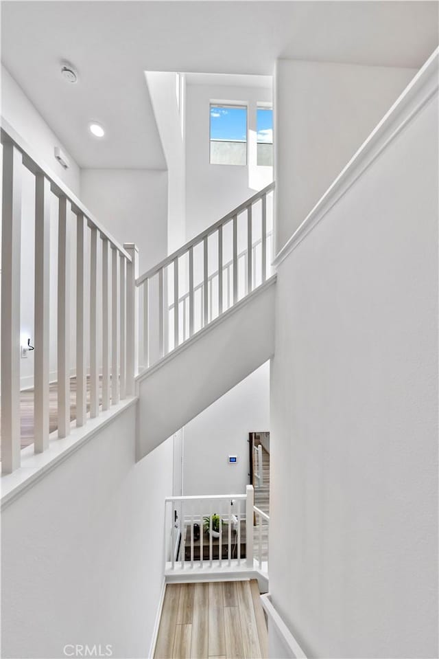 staircase featuring hardwood / wood-style flooring and a high ceiling