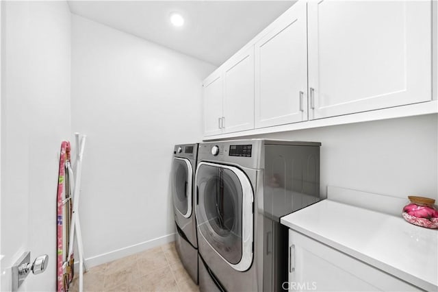 laundry area with washer and dryer, cabinets, and light tile patterned flooring