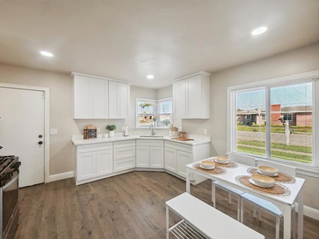 kitchen featuring dark wood-type flooring, sink, white cabinets, and gas range