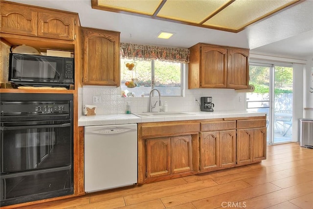 kitchen with sink, black appliances, plenty of natural light, and tile counters