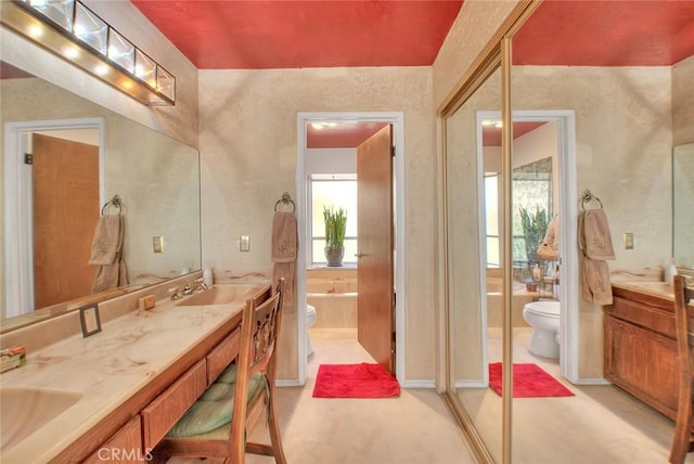 bathroom featuring a tub to relax in, toilet, and vanity