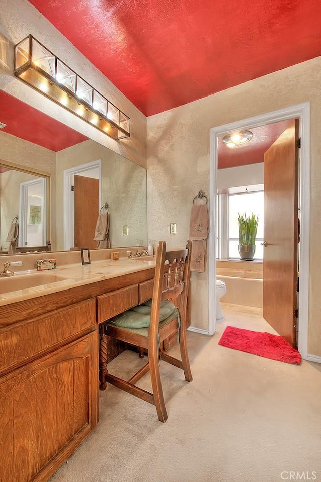 bathroom featuring toilet, vanity, and a bath