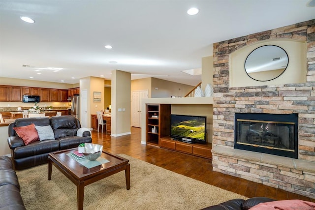 living room featuring dark hardwood / wood-style floors and a stone fireplace