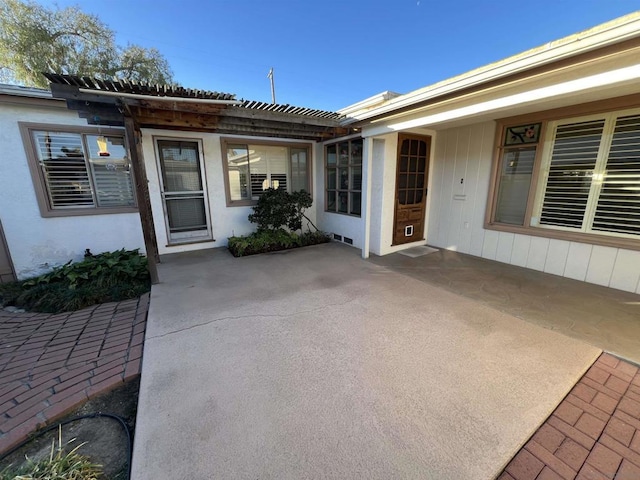 doorway to property with a patio area and a pergola