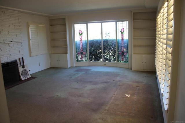 unfurnished living room featuring built in shelves, a fireplace, and carpet