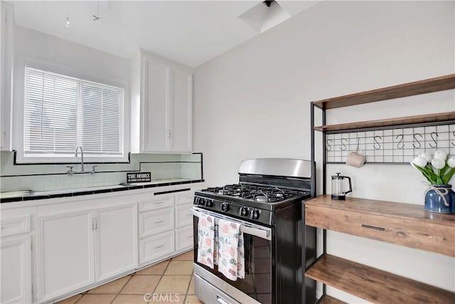 kitchen featuring gas range, light tile patterned floors, white cabinetry, and decorative backsplash