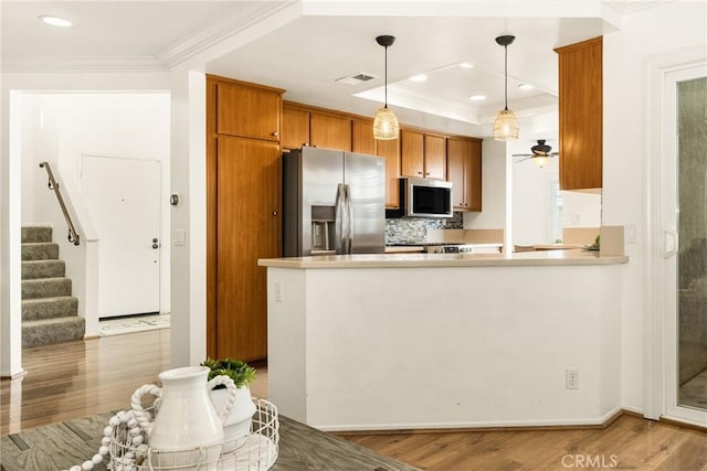 kitchen featuring stainless steel appliances, hanging light fixtures, kitchen peninsula, and decorative backsplash