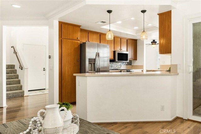 kitchen featuring decorative light fixtures, kitchen peninsula, appliances with stainless steel finishes, and backsplash