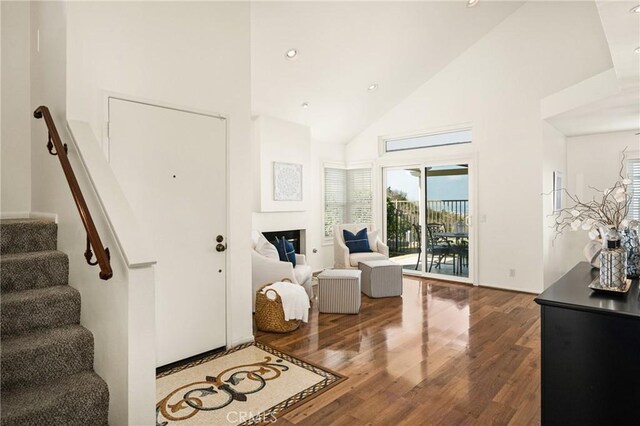 foyer entrance with wood-type flooring and high vaulted ceiling