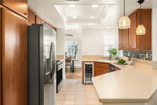 kitchen with kitchen peninsula, pendant lighting, stainless steel appliances, beverage cooler, and a tray ceiling