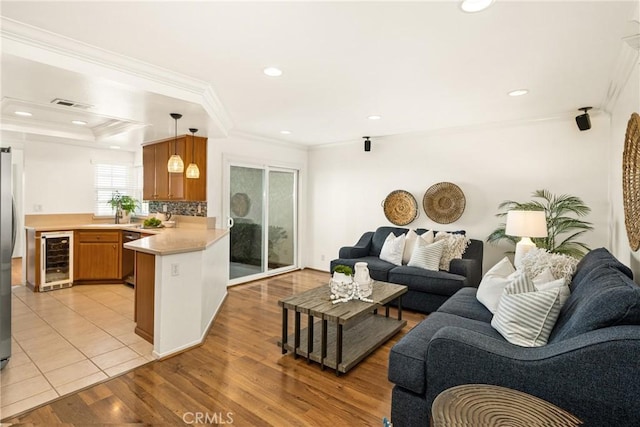 living room featuring light hardwood / wood-style flooring, beverage cooler, and crown molding