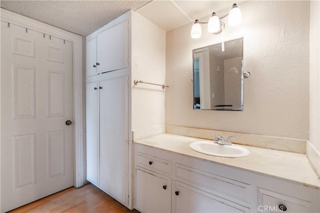 bathroom with wood-type flooring, vanity, and a textured ceiling