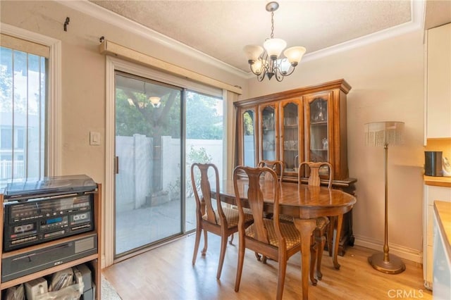 dining room with ornamental molding, an inviting chandelier, and light hardwood / wood-style floors