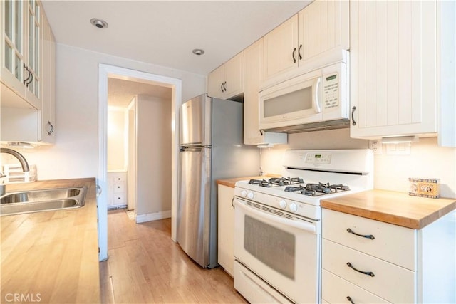 kitchen featuring butcher block countertops, sink, white appliances, white cabinets, and light wood-type flooring