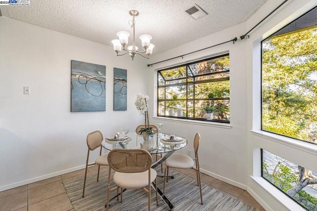 tiled dining room with a textured ceiling and a notable chandelier