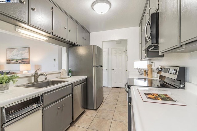 kitchen featuring sink, stainless steel appliances, light tile patterned floors, and gray cabinetry