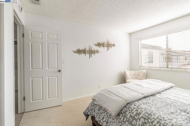 bedroom with light colored carpet and a textured ceiling