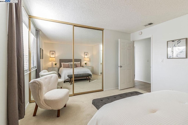 carpeted bedroom featuring a textured ceiling and a closet