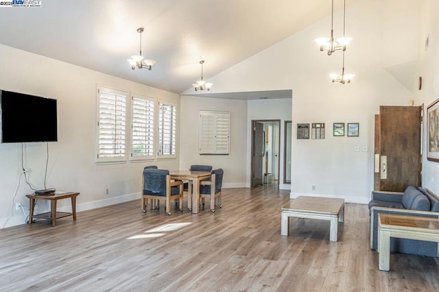 living room with high vaulted ceiling, light wood-type flooring, and an inviting chandelier