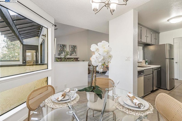 dining room featuring a chandelier, a textured ceiling, light tile patterned floors, and lofted ceiling