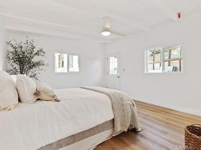 bedroom with a ceiling fan, beam ceiling, baseboards, and wood finished floors