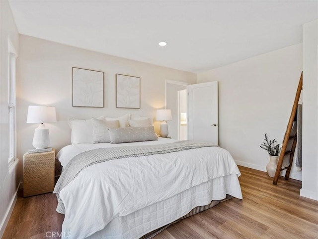 bedroom with baseboards, wood finished floors, and recessed lighting